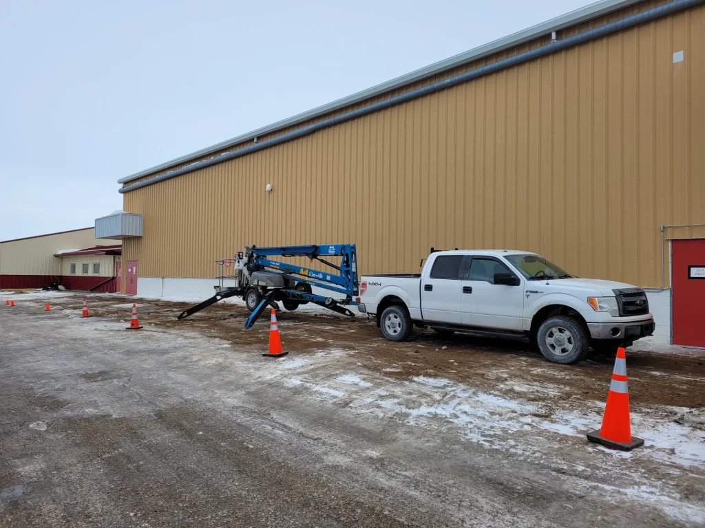 Boom lift positioned for second-storey window installation on a residential building