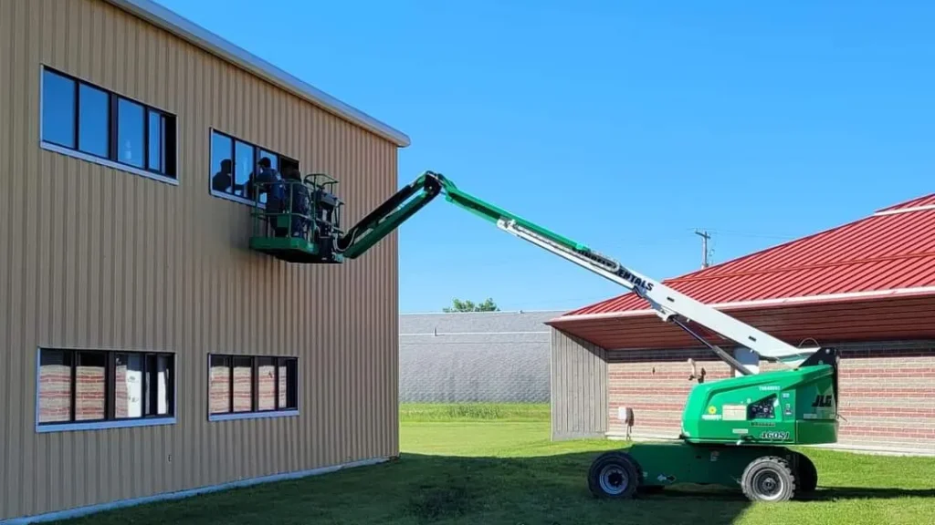 Boom lift positioned for second-storey window installation on a residential building
