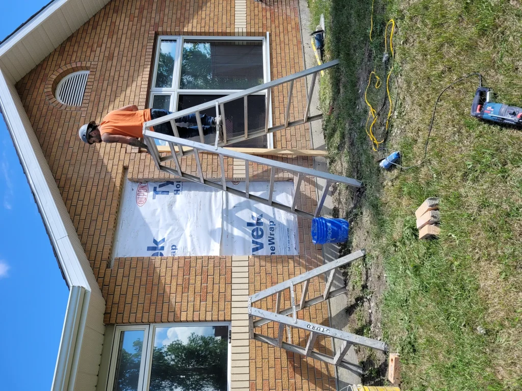 Boom lift positioned for second-storey window installation on a residential building